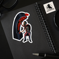 Sticker of a zombie playing a slot machine on a black notebook with a pen and another sticker.