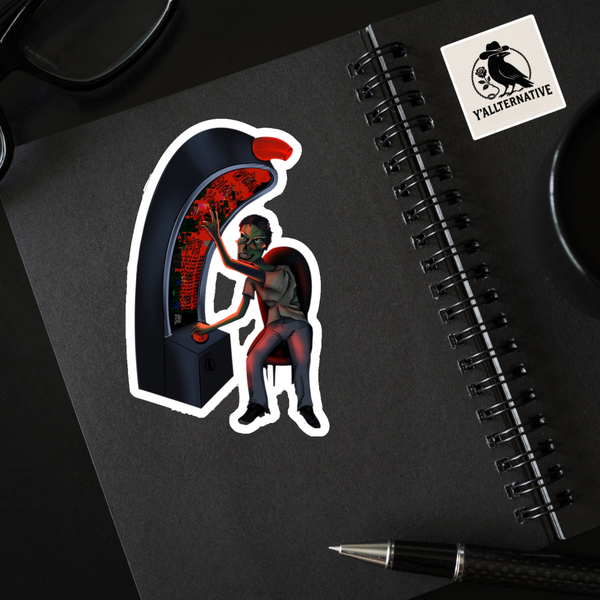 Sticker of a zombie playing a slot machine on a black notebook with a pen and another sticker.