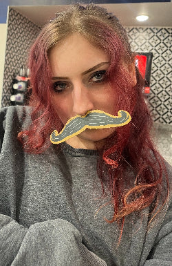 Picture of the Artisti - Woman with a bad fake mustache filter over their mouth in an indoor setting