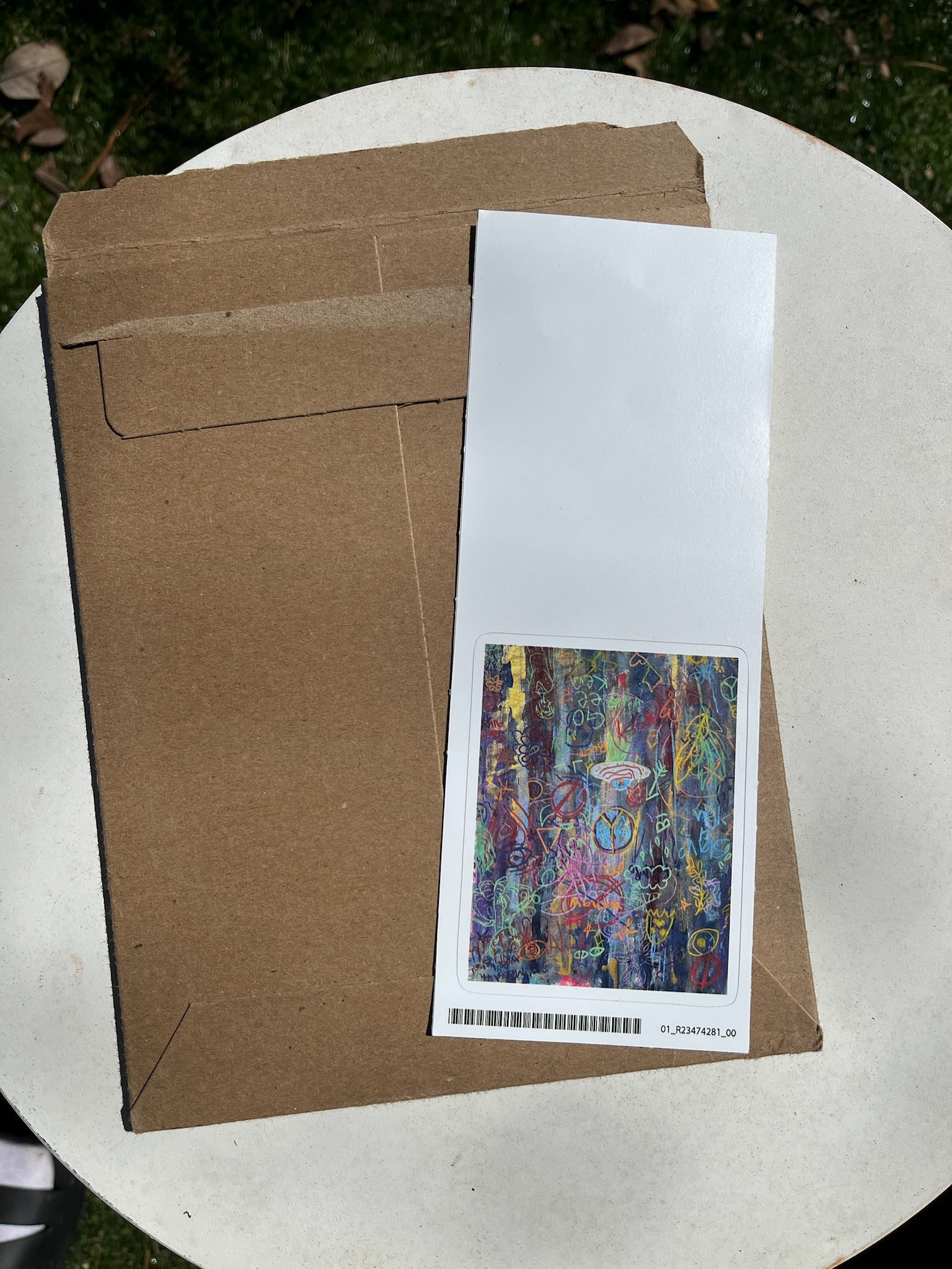 cardboard envelope with a colorful graffiti sticker on a white surface outdoors